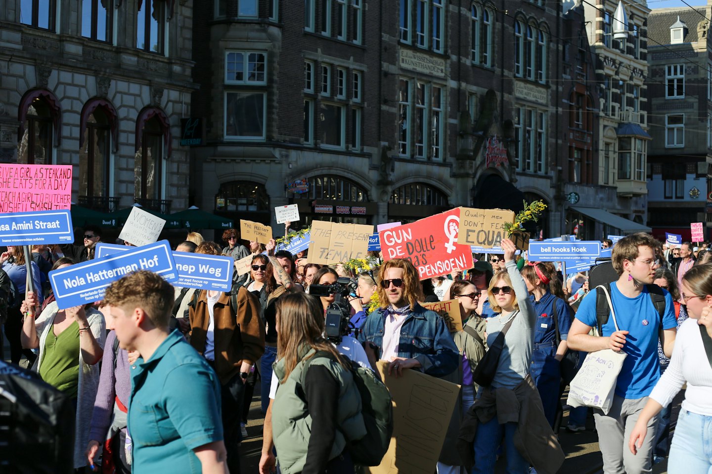 A group of people marches down a city street holding protest signs.
